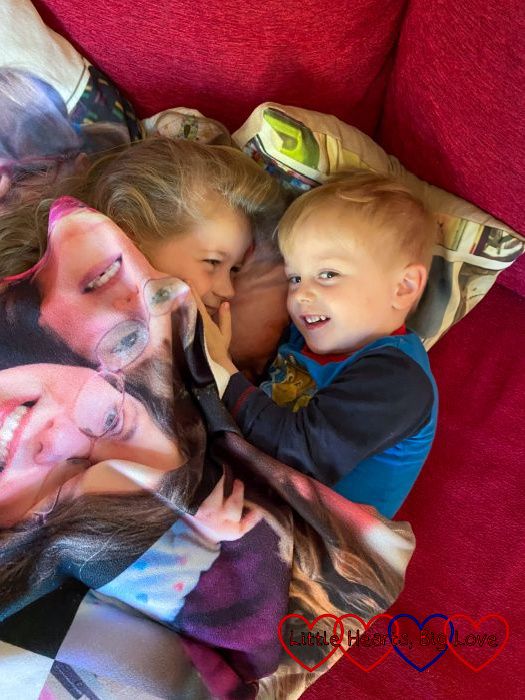 Sophie and Thomas snuggled up together under a blanket with photos of Jessica on