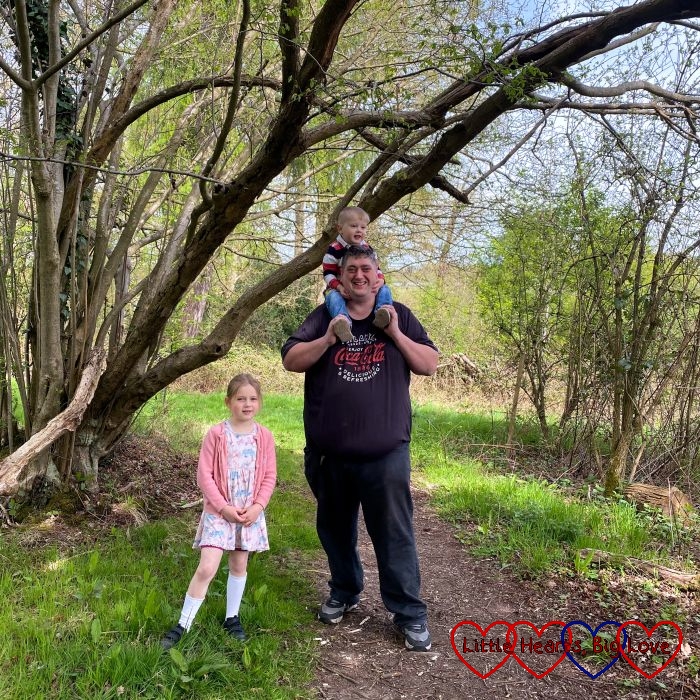 Daddy with Thomas on his shoulders and Sophie next to him on a footpath in the woods