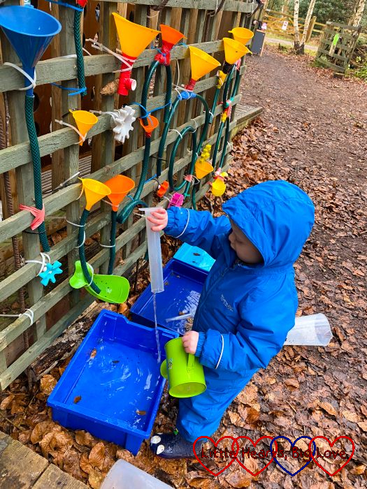 Thomas pouring water from a tube in front of the water wall at Tots Go Wild