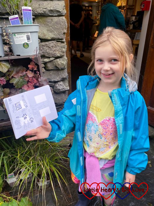 Sophie holding up her National Trust passport with Beatrix Potter character stamps