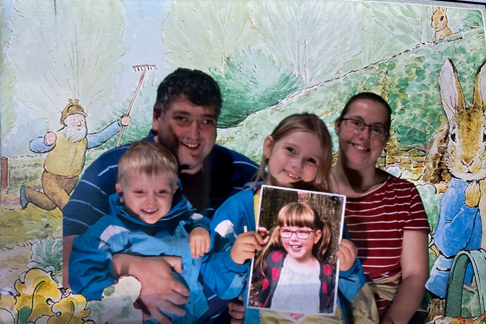 Hubby, Thomas, Sophie (holding a picture of Jessica) and me in front of a Beatrix Potter themed backdrop