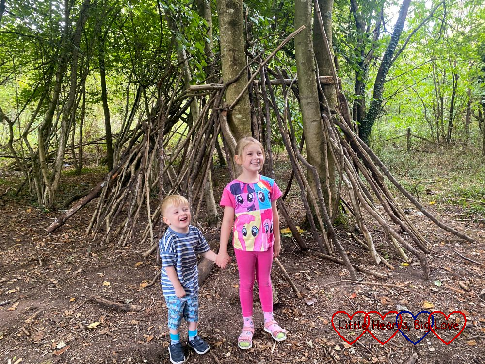 Sophie and Thomas standing in front of a den in the woods