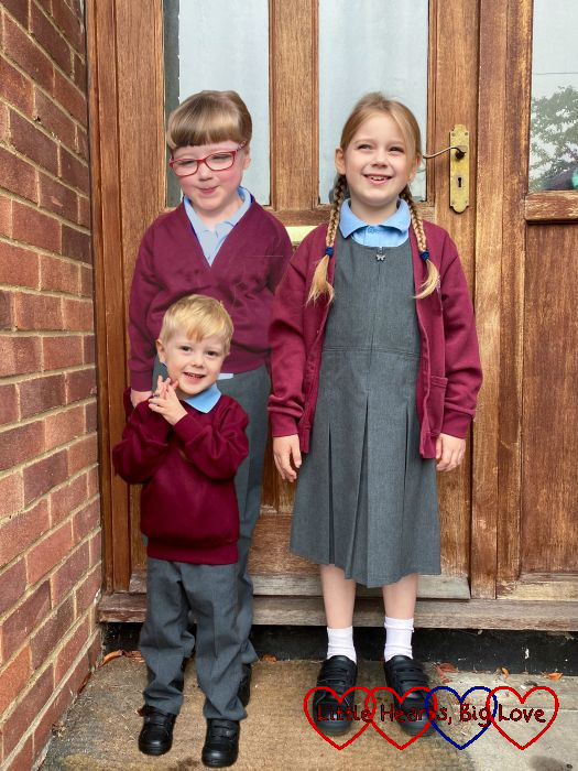 Sophie and Thomas standing in front of the door on their first day back at school with Jessica photoshopped standing behind them