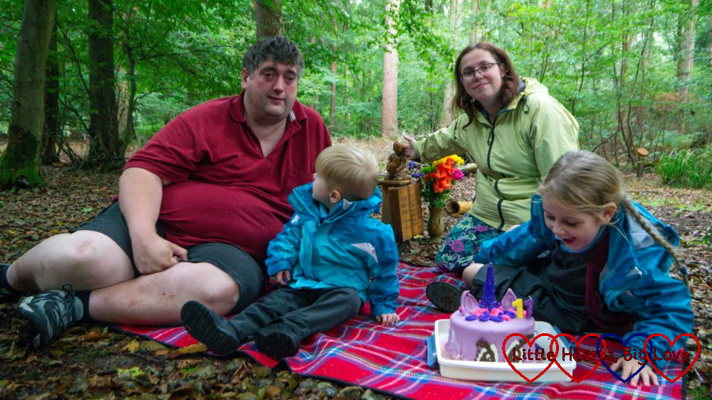 My husband with Thomas looking at him; me and Sophie sitting on a picnic blanket at Jessica's forever bed with her Twilight Sparkle unicorn birthday cake on the picnic blanket in front of us
