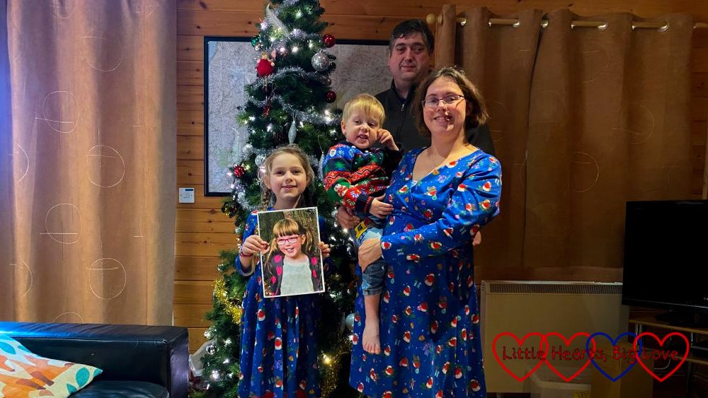 Me (holding Thomas), hubby and Sophie (holding a photo of Jessica) standing in front of a Christmas tree