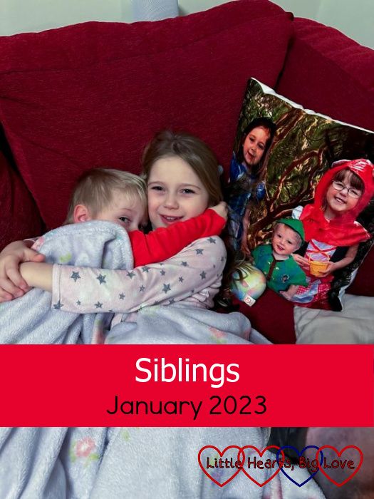 Thomas snuggled up to Sophie under a blanket on the sofa with a photo cushion of Thomas, Jessica and Sophie wearing fairytale costumes next to them - "Siblings - January 2023"