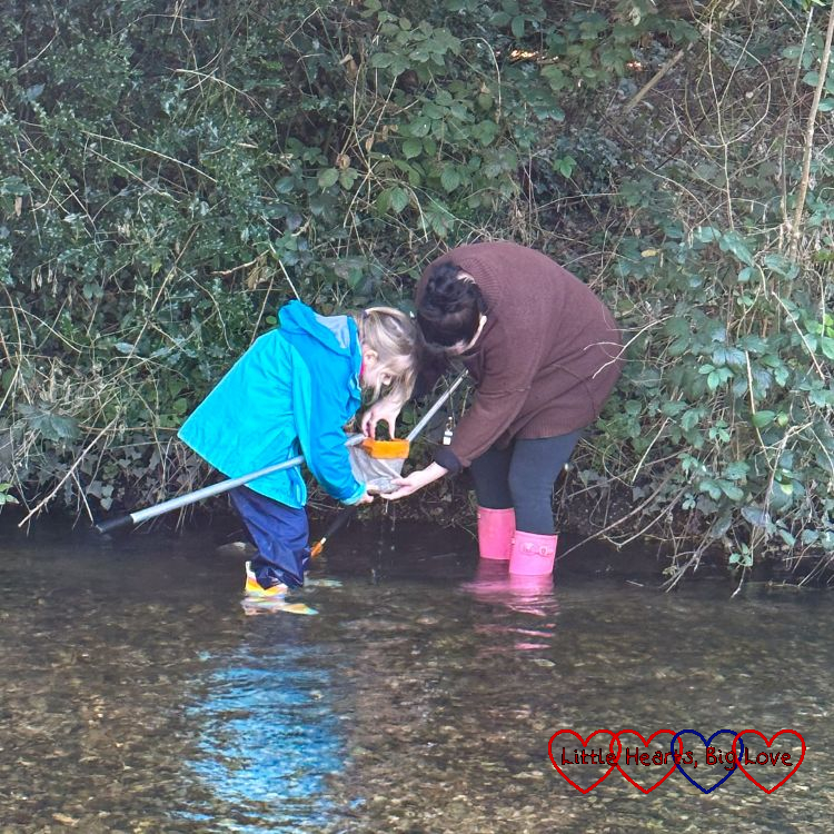 Sophie and the activity leader standing in the river looking in Sophie's net