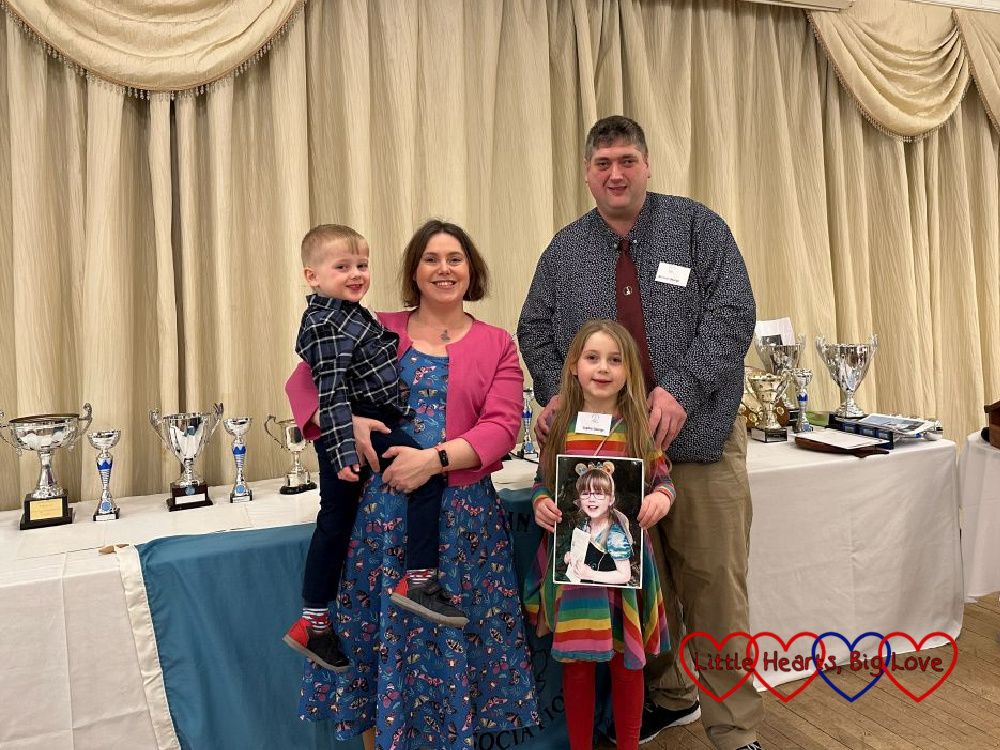 Me (holding Thomas), my husband and Sophie (holding a picture of Jessica) standing in front of the trophy table at the Land's End - John O'Groats Association Annual Dinner