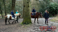 Sophie and Thomas riding ponies through the woods