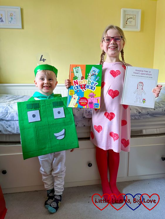 Thomas wearing his Numberblock Four costume and holding his Numberblocks annual next to Sophie dressed as Jessica holding my book 'Jessica has a heart operation'