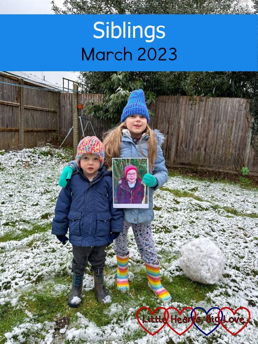 Sophie and Thomas standing in the snow in the garden with Sophie holding a photo of Jessica - "Siblings - March 2023"