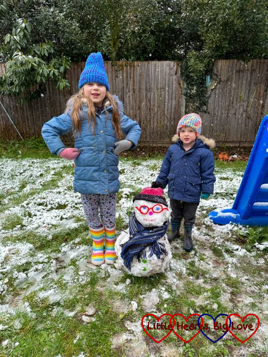Sophie and Thomas standing in the snow in the garden with a "snow Jessica" in between them