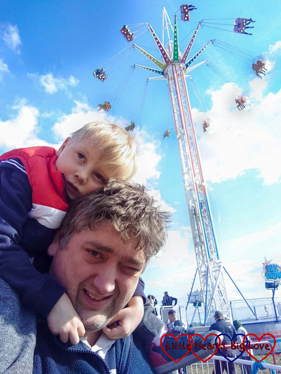 Daddy with Thomas on his shoulders standing in front of the 'Air Swing' ride at the fair