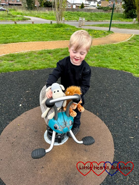 Thomas playing with his toy sheep and lion at the park