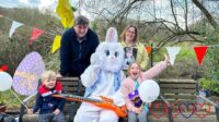 Thomas, my husband, me (holding a photo of Jessica) and Sophie sitting and standing around the Easter bunny who is sitting on a bench