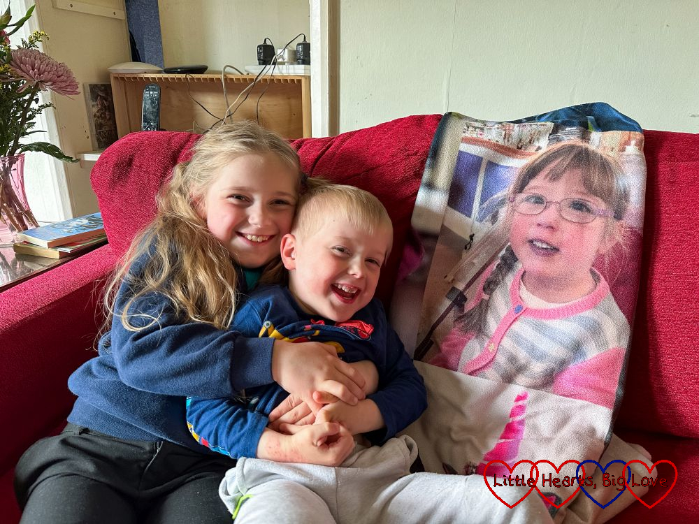 Sophie and Thomas having cuddles on the sofa next to a photo of Jessica from her photo-blanket