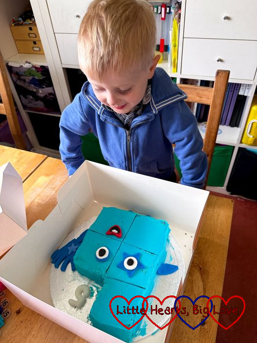 A smiley Thomas looking at his Numberblock Five birthday cake