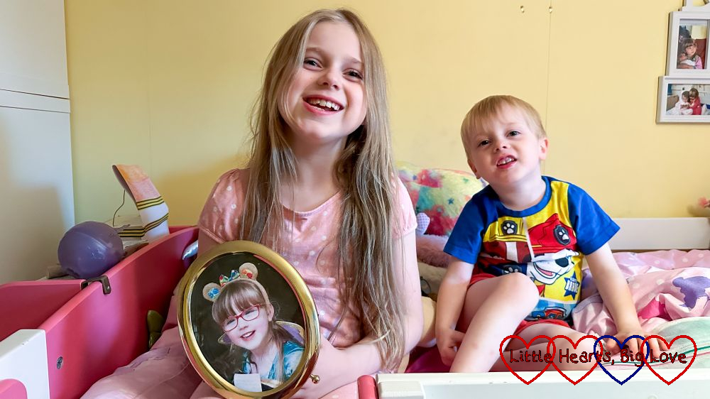 Sophie and Thomas sitting together on Sophie's bed with Sophie holding a picture of Jessica