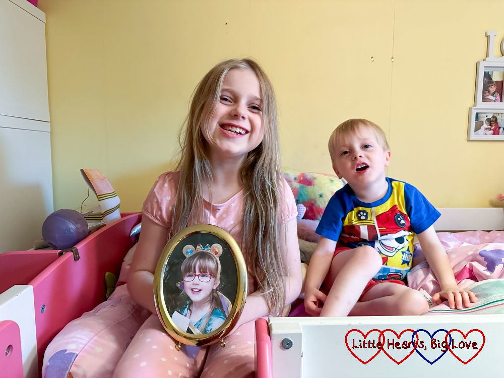 Sophie and Thomas sitting together on Sophie's bed with Sophie holding a picture of Jessica