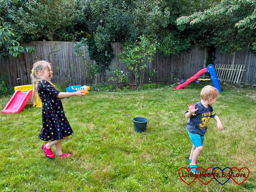 Sophie squirting a water gun at Thomas in the garden