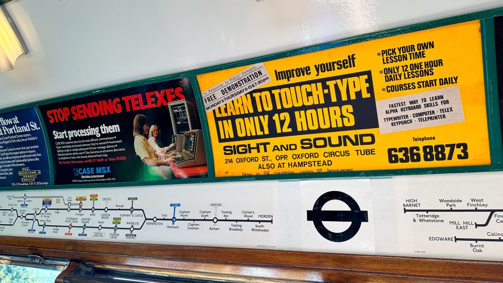 Adverts on a vintage tube train advertising courses to "learn to touch-type in only 12 hours", and an advert to "Stop sending telexes. Start processing them."