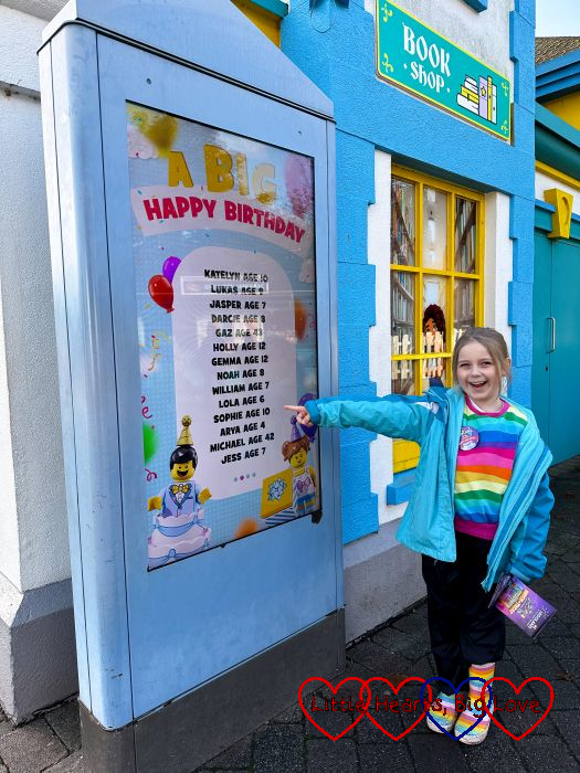 Sophie pointing at her name on the birthday board at Legoland.