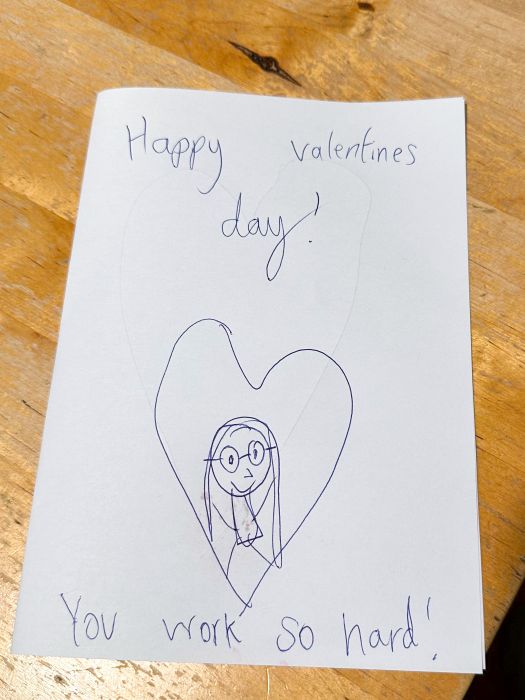 A hand-made Valentine's card with a drawing of me inside a heart and the words 'Happy Valentine's Day. You work so hard!"