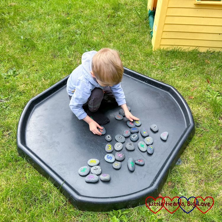 Thomas playing with his number rocks in the tuff tray