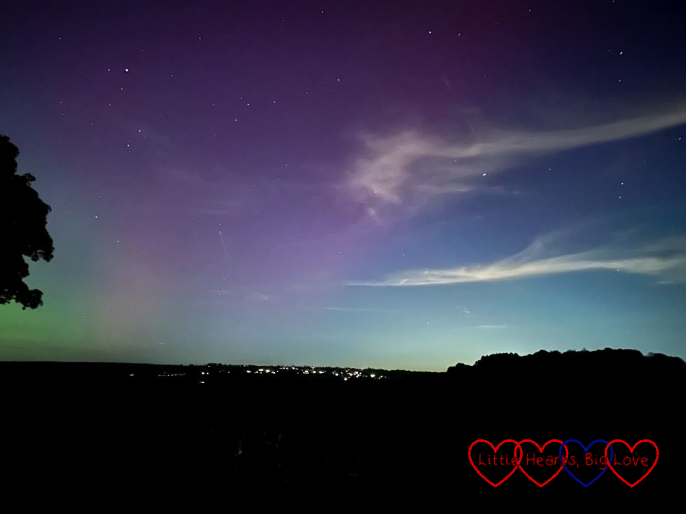 Faint purple and green aurora borealis in a starry night sky