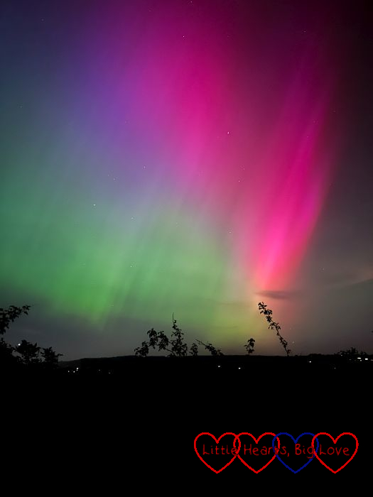 Bright pink, purple and green aurora borealis in the night sky